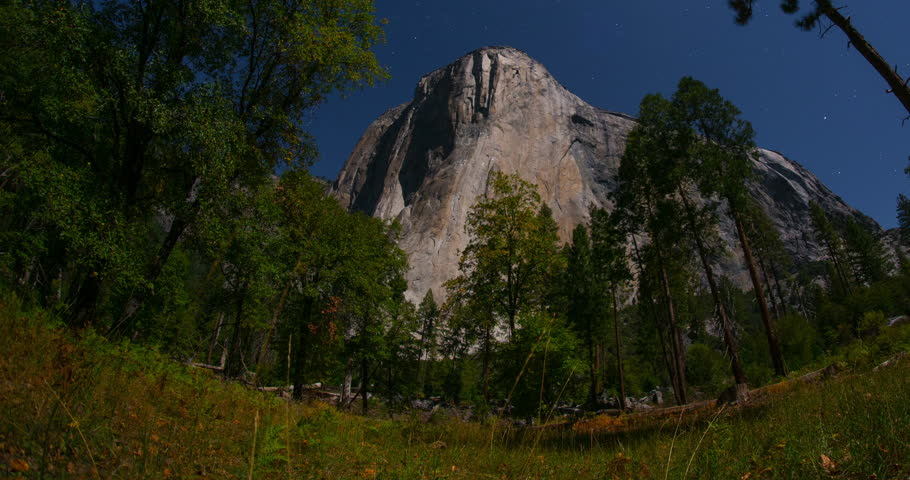 El Capitan under a bright moonlit sky in Yosemite National Park, California. Long-exposure timelapse capturing nature’s motion over iconic granite cliff in high definition 4K. 