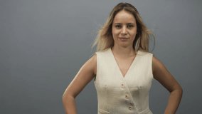 Woman waving hand with open palm in gray studio setting wearing sleeveless vest and looking at camera; welcoming smile. - Powered by Shutterstock - Get 15% off with code: PIKWIZARD15