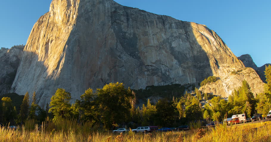 Sunset timelapse over El Capitan in Yosemite National Park, California. The sky transitions from bright blue to warm golden tones, illuminating the iconic granite cliffs in perfect clarity