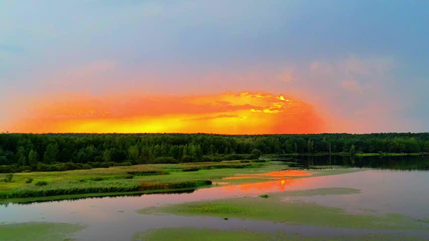 Aerial drone view of river and wetlands at sunset, golden sky reflected in calm water, peaceful landscape.