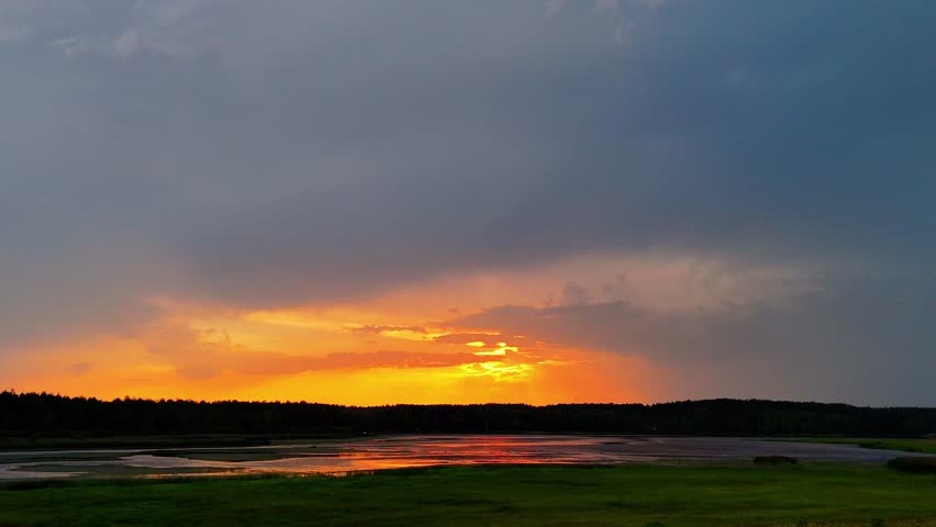Drone shot of sunset over lake and wetlands, vibrant sky colors and golden light reflection.