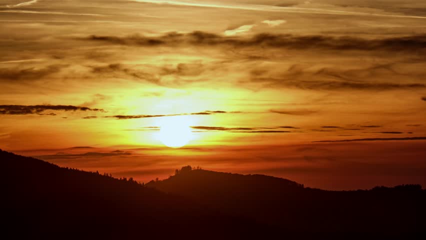 Timelapse of a dramatic big sunset over a mountain ridge with vibrant clouds