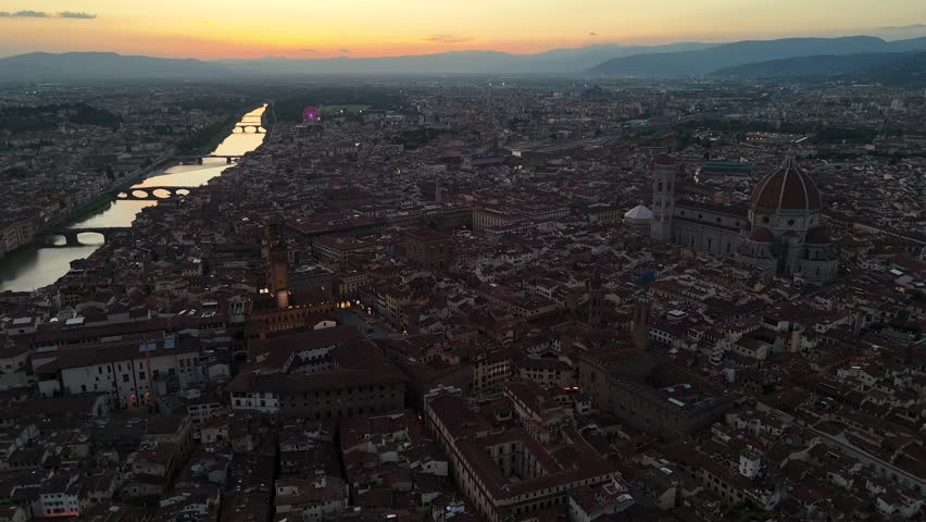 Aerial shot over Florence — the city’s rooftops, bridges, and cathedral bathed in golden twilight