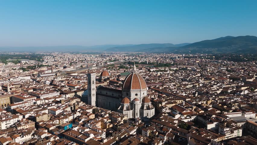 Drone flies over Florence on a sunny day, revealing the Duomo rising above the city’s terracotta rooftops