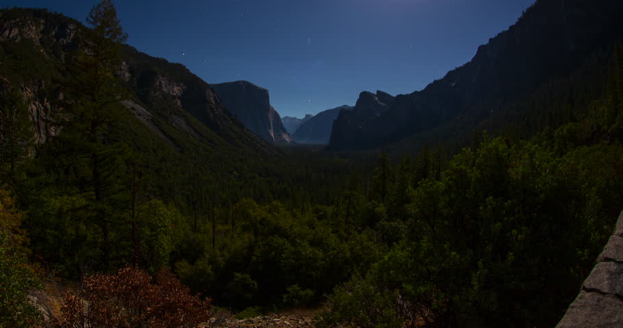 A stunning night timelapse from Tunnel View in Yosemite National Park, California. Moonlight illuminates El Capitan, Half Dome, and Cathedral Rocks under a clear starry sky across the vast valley.