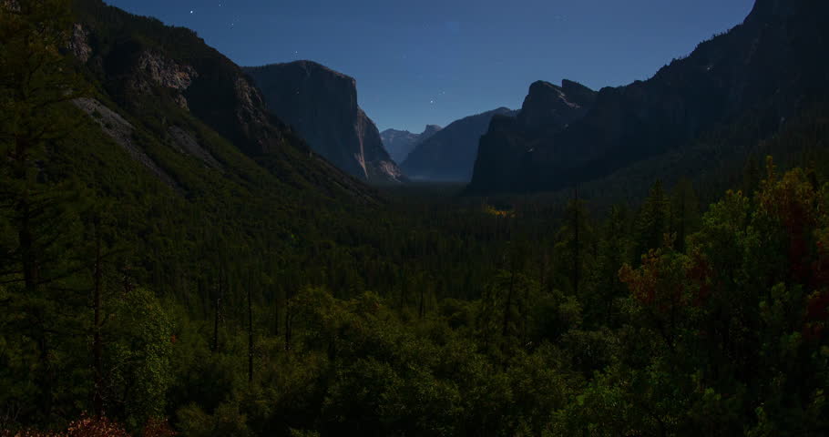 A stunning night timelapse from Tunnel View in Yosemite National Park, California. Moonlight illuminates El Capitan, Half Dome, and Cathedral Rocks under a star trail sky across the vast valley.