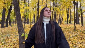 Young woman twirls joyfully in autumn park, golden leaves swirl around, forest in background filled with yellow foliage, feeling of freedom and happiness in fall nature. - Powered by Shutterstock - Get 15% off with code: PIKWIZARD15