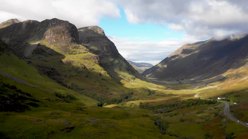 Scenic drone view of a road winding through highlands in Scotland near Glencoe - Nature and travel concepts with the Three Sisters of Glencoe mountains on the left on a beautiful day
