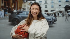 Young woman smiling with basketball on a busy city street, capturing a dynamic outdoor urban scene with cars and buildings in the background, embodying joyful urban lifestyle. - Powered by Shutterstock - Get 15% off with code: PIKWIZARD15