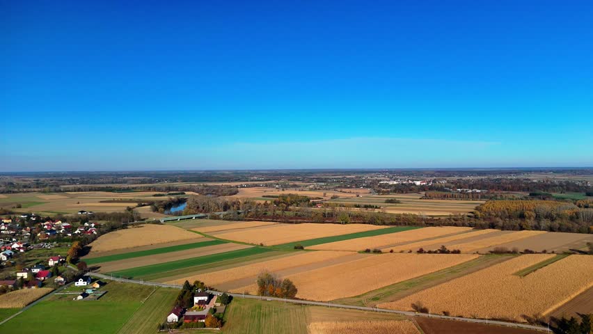 Wide panoramic aerial view of rural countryside with fields, river and blue clear sky.