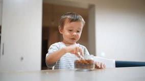 The young boy sits at the table, enjoying snacks from a glass jar. The boy's small hands reach for the tasty treats while he savors the moment in a cozy kitchen. - Powered by Shutterstock - Get 15% off with code: PIKWIZARD15