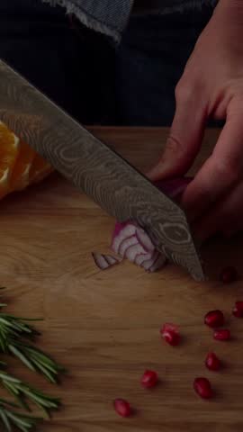 Slicing a red onion on a wooden board. A craft knife slices the onion.