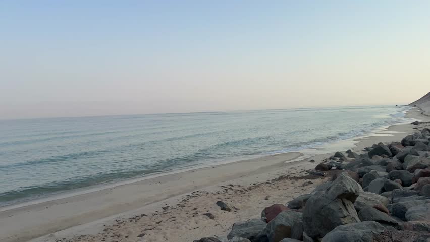 The magical coast of the Gulf of Aqaba in Taba, Egypt, with colorful rocks, sandy shore, clear blue water, and vibrant sky, creating a peaceful natural seaside landscape.