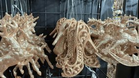 Glittering rose gold christmas tree decorations in various shapes like reindeer, sleighs, peacocks, and snowflakes hanging for sale in a store during the festive holiday shopping season - Powered by Shutterstock - Get 15% off with code: PIKWIZARD15