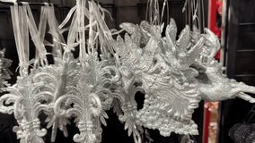 Shiny silver and purple christmas decorations with glitter hanging on display in a store. The assortment of festive baubles includes reindeer, snowflakes, bells, and other holiday shapes - Powered by Shutterstock - Get 15% off with code: PIKWIZARD15