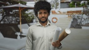 Man holding blueprints outdoors at a luxurious hotel resort pool, showcasing modern leisure and business integration in a stylish environment surrounded by nature. - Powered by Shutterstock - Get 15% off with code: PIKWIZARD15