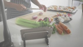 Woman slicing onion and checking tablet, causing ripple overlay intensifying for kitchen prep. Cooking, culinary, healthy, fresh, domestic, modern, lifestyle - Powered by Shutterstock - Get 15% off with code: PIKWIZARD15