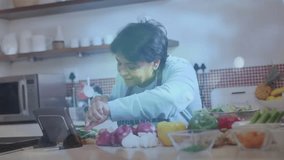 Senior cook tapping tablet slicing peppers, onions following recipe with water effect guiding steps. Vegetables, technology, culinary, rustic, wellness, nutrition, home - Powered by Shutterstock - Get 15% off with code: PIKWIZARD15