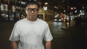 Man with glasses closes eyes on busy city street at night under neon lights; serenity reflection mindfulness. - Powered by Shutterstock - Get 15% off with code: PIKWIZARD15