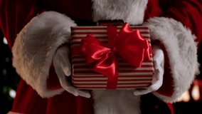 A festive scene featuring a Santa Claus figure holding a wrapped Christmas gift with a red ribbon. A warm festive atmosphere for New Year or Christmas. Slow motion. - Powered by Shutterstock - Get 15% off with code: PIKWIZARD15