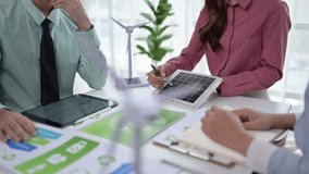 Business team meeting to discuss renewable energy projects with solar panel and wind turbine models - Powered by Shutterstock - Get 15% off with code: PIKWIZARD15