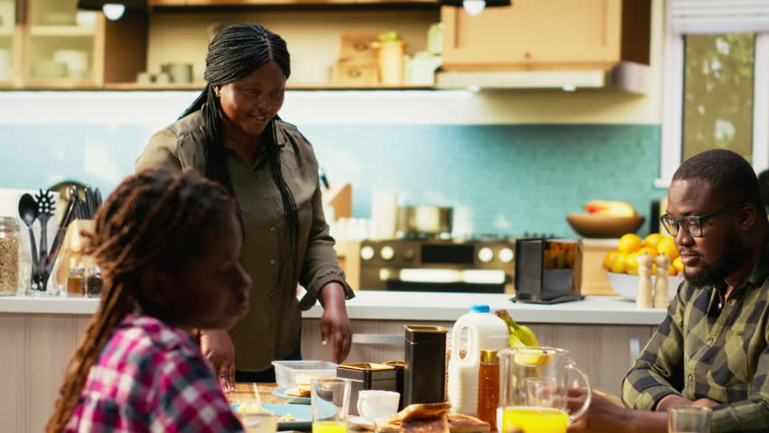Mother preparing packed lunch in box for children at school, family serving breakfast early in the morning. Back to school meal prep with sandwich and fruits, morning routine at home. Camera B.