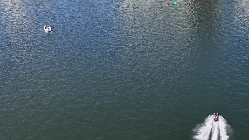 Drone captures jetski and speedboat racing across open ocean, leaving dynamic white wake trails
