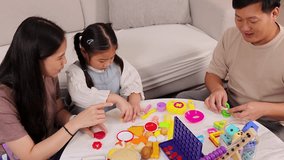Asian parents and young daughter play with colorful educational toys at home in bright living room. - Powered by Shutterstock - Get 15% off with code: PIKWIZARD15