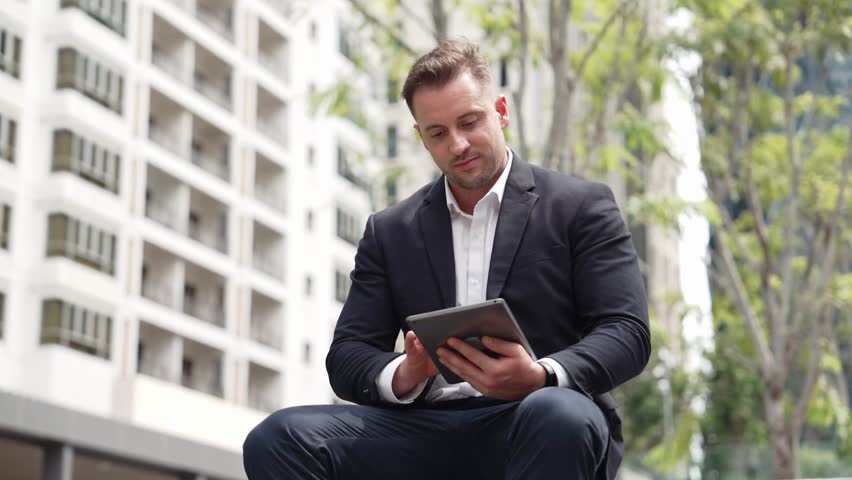 Close up of business people working on tablet while sitting at green city. Low angle camera of manager using his tablet to browsing and searching financial data analysis while remote working. Urbane. - Powered by Shutterstock - Get 15% off with code: PIKWIZARD15