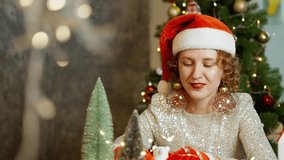 Festive portrait of woman in Santa hat by Christmas tree with glowing lights. Scene radiates holiday cheer, happy emotions and magical winter celebration spirit. - Powered by Shutterstock - Get 15% off with code: PIKWIZARD15