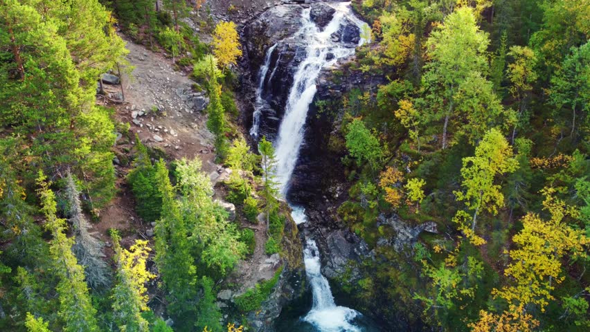 Beautiful autumn waterfall in the mountains beyond the Arctic Circle, in the north, in the Khibiny Mountains, Murmansk Region. Panoramic view of a beautiful autumn waterfall in the mountains, 4k Drone
