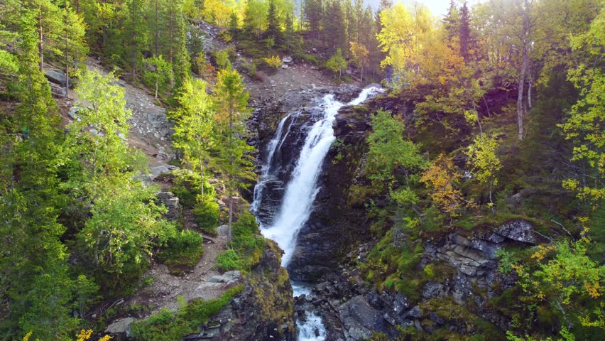 Beautiful autumn waterfall in the mountains beyond the Arctic Circle, in the north, in the Khibiny Mountains, Murmansk Region. Panoramic view of a beautiful autumn waterfall in the mountains, 4k Drone