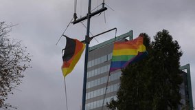 Looking up to German flag and LBGTQ rainbow flag at German city of Frankfurt am Main on a cloudy autumn day. Movie shot November 3rd, 2025, Frankfurt am Main, Germany. - Powered by Shutterstock - Get 15% off with code: PIKWIZARD15