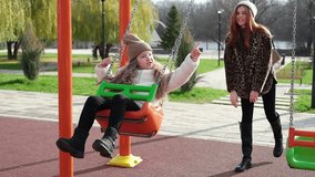 Mom and her daughter swinging on swing in autumn park. Happy family, child outdoors, weekend. Child girl, sits on swing smiles. Playground in fall - Powered by Shutterstock - Get 15% off with code: PIKWIZARD15