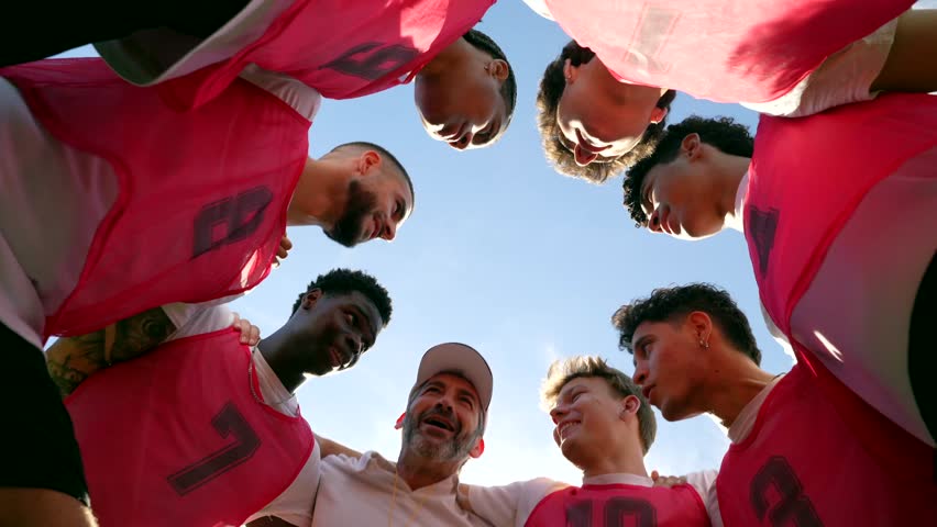Multiethnic youth soccer team and coach in a tight huddle, listening to a motivating pep talk before a sunny match, showing unity, teamwork and focused team spirit - Powered by Shutterstock - Get 15% off with code: PIKWIZARD15