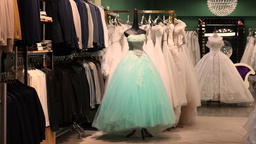 Store preparing for prom and wedding season with affordable colorful dresses and suits for bridesmaids and guests, displayed on racks, offering stylish festive outfits without branded labels.