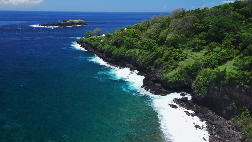 Aerial view of rocky coastline with ocean waves on sunny day in Bali, paradise coastline