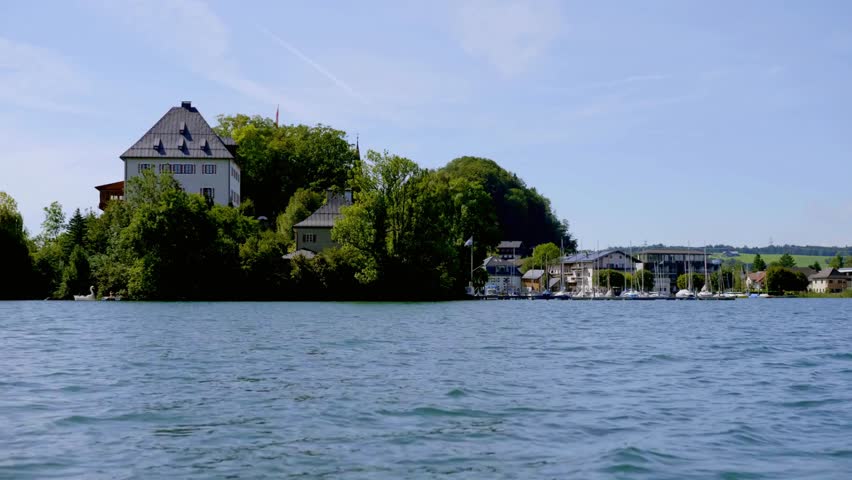 Lakeside view of a historic building surrounded by trees on a sunny summer day