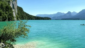 Tranquil turquoise lake surrounded by mountains and lush greenery on a sunny day - Powered by Shutterstock - Get 15% off with code: PIKWIZARD15