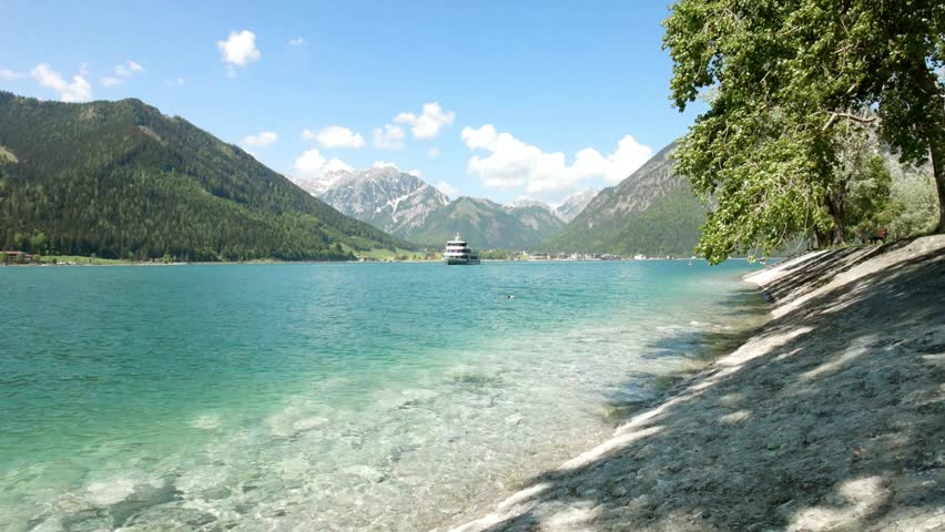 Serene lake view with mountains and a boat under a bright blue sky landscape