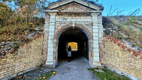 Tourist female walks into arched brick entrance tunnel of Daugavgrīva Fortress in Riga, Latvia - Powered by Shutterstock - Get 15% off with code: PIKWIZARD15