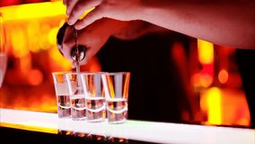 Skilled barman preparing layered cocktail shots at a bar at night, pouring colorful liquor to create beautiful gradient drinks under warm light. - Powered by Shutterstock - Get 15% off with code: PIKWIZARD15