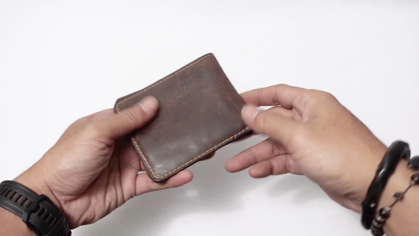 Empty wallet without any cash left. A worn brown leather wallet is opened by two hands, revealing a empty.