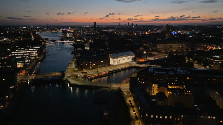 Aerial drone view of Knippel Bascule Bridge in Copenhagen at night, showcasing illuminated architecture, cityscape, and urban nightlife.