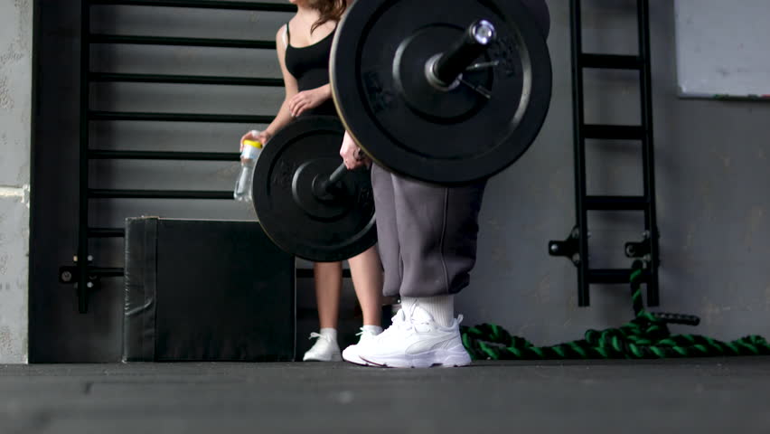 Lifting barbell, woman in gym focusing on strength training workout. Exercise, fitness, weightlifting, bodybuilding, muscles, athlete
