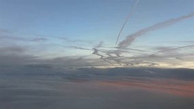 An aerial view of many jet contrails fading in a pastel color sky at sunrise, with a golden light through layers of ethereal stratus clouds. Footage taken from a jet cockpit. - Powered by Shutterstock - Get 15% off with code: PIKWIZARD15