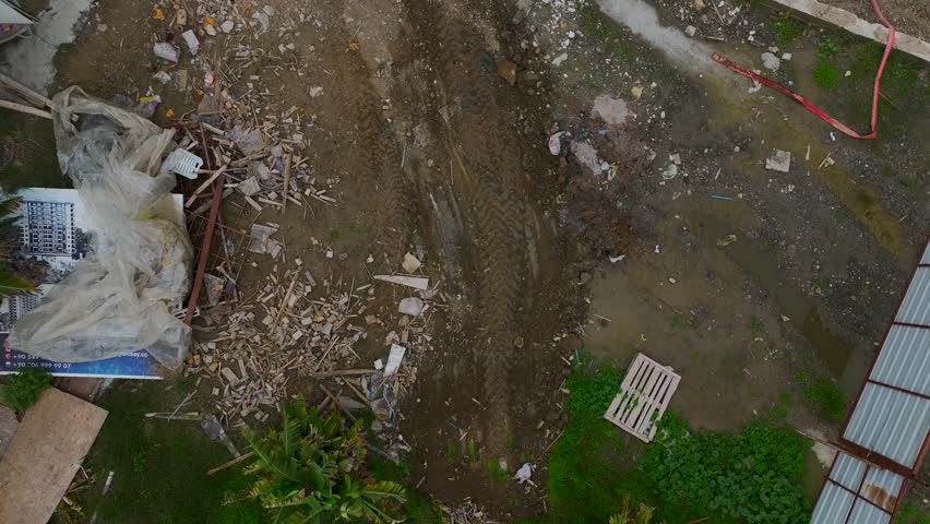 Aerial Video Earthmoving tractor with a front bucket levels the ground at a construction site, preparing it for buildings.