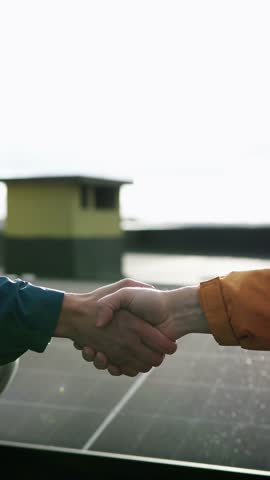 Handshake over solar panels, symbol of partnership in renewable energy. Vertical video shot.