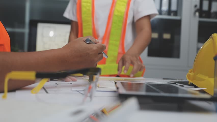 team of multiethnic architects working on construction plans in meeting room engineers discussing on project in office mature businessman and woman standing around table working on blueprint no logos