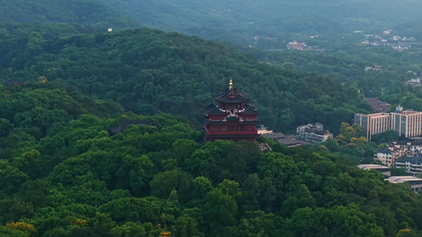 Aerial view of Chenghuang pagoda at sunset over Xihu lake in Hangzhou featuring mountains and lush green trees